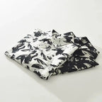 Folded black and white patterned shirts on a light gray background