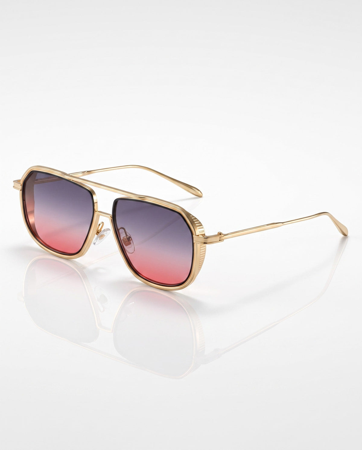Gold-toned aviator sunglasses with a flat top bar and gradient purple-to-pink lenses, reflecting on a white surface.