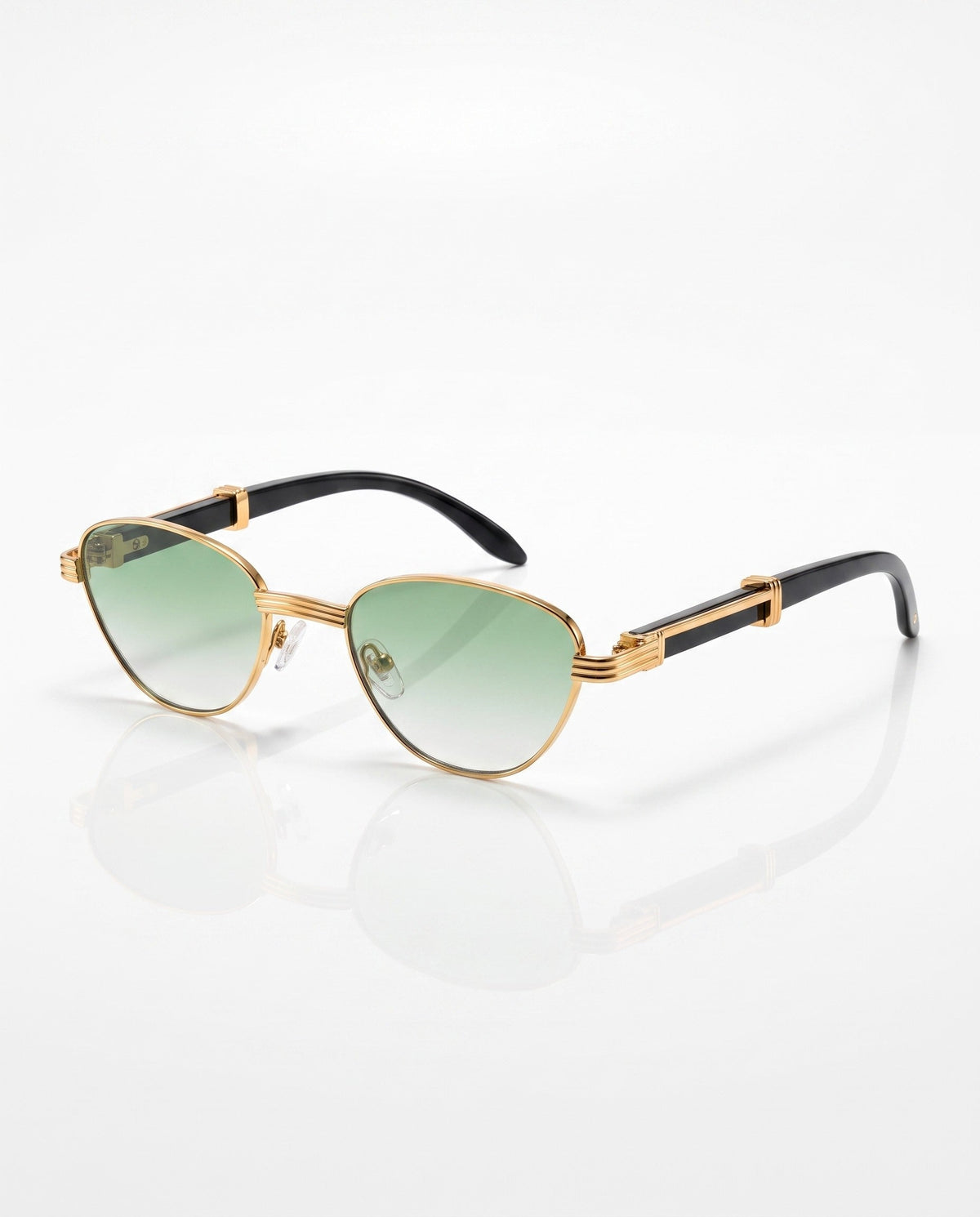 Gold-framed cat-eye sunglasses with green gradient lenses and black arms, detailed with gold accents, rest on a white surface.