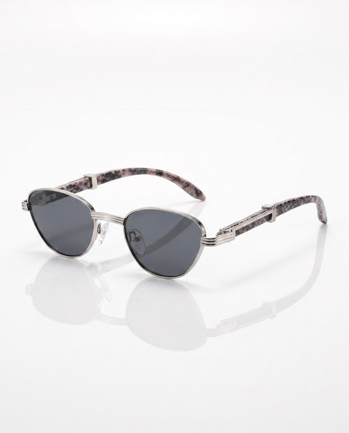 Silver metal cat-eye sunglasses with dark lenses and spotted animal print arms, reflecting on a white surface.