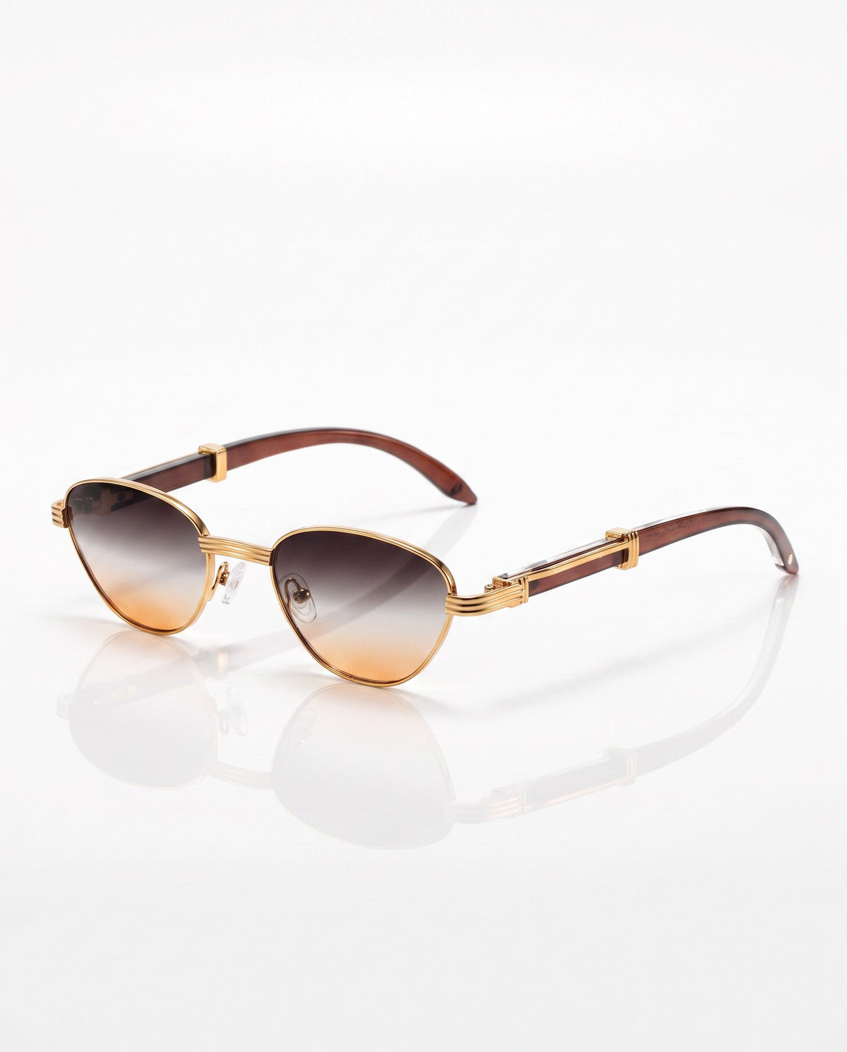 Gold cat-eye sunglasses with brown gradient lenses and wood-look temples, posed on a reflective white surface.