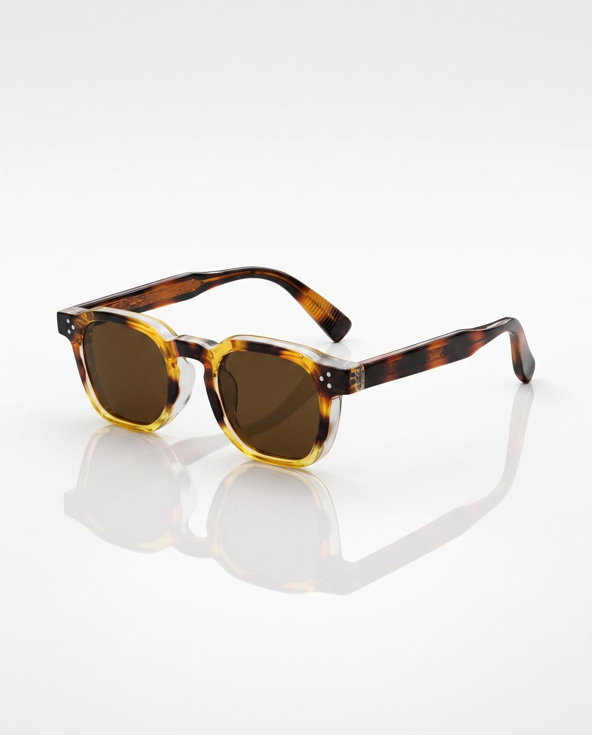 Square-frame sunglasses feature amber and brown tortoiseshell acetate with dark lenses, showcased on a reflective white surface.