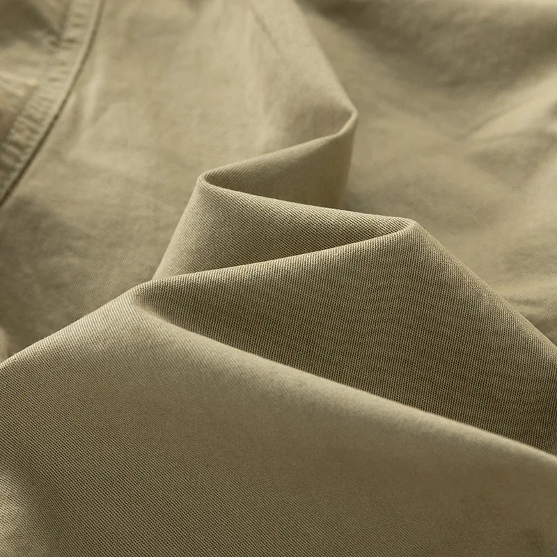 Close-up of khaki cotton twill fabric with visible diagonal weave and soft, elegant folds.