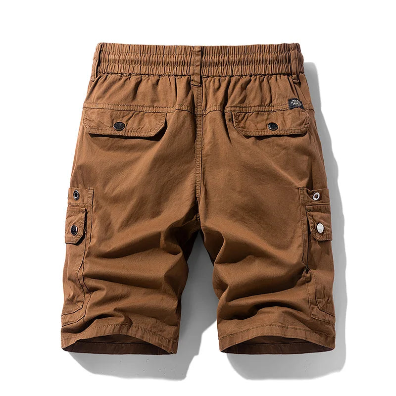 Back view of brown cotton cargo shorts with an elastic waist, flap back pockets, and buttoned side cargo pockets.