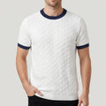Man wearing a white knit short-sleeve shirt with a diamond texture pattern and navy ribbed collar and sleeve cuffs.