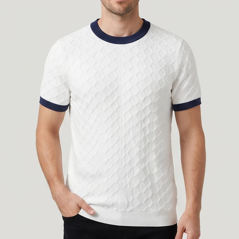 Man wearing a white knit short-sleeve shirt with a diamond texture pattern and navy ribbed collar and sleeve cuffs.