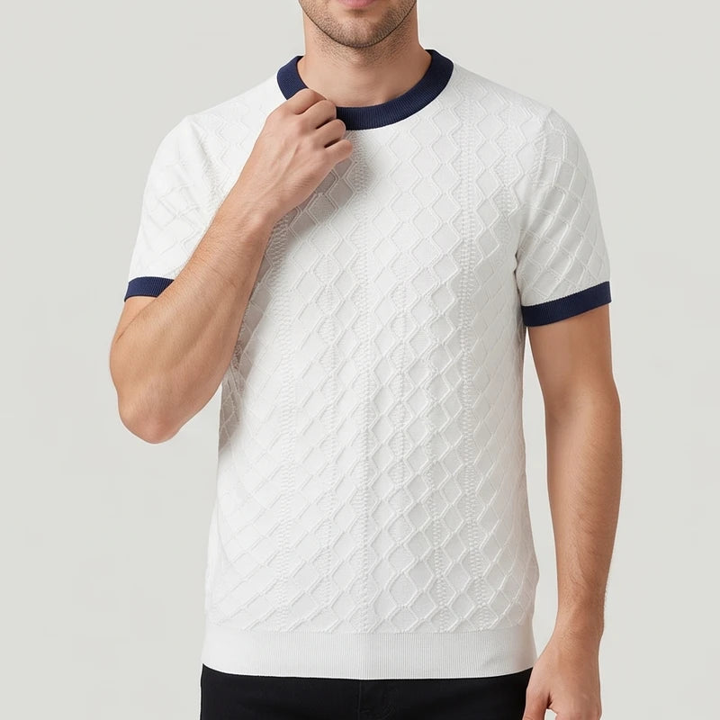 Man wearing a white short-sleeve knit shirt with a textured diamond pattern and navy trim on the collar and cuffs.