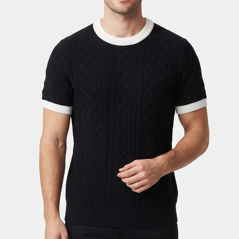 Man wearing a black short-sleeved cable knit crewneck shirt with white trim on the collar and cuffs.