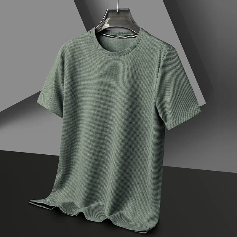 Flat lay of a textured sage green short-sleeve crewneck shirt hanging on a hanger against a dark gray background.