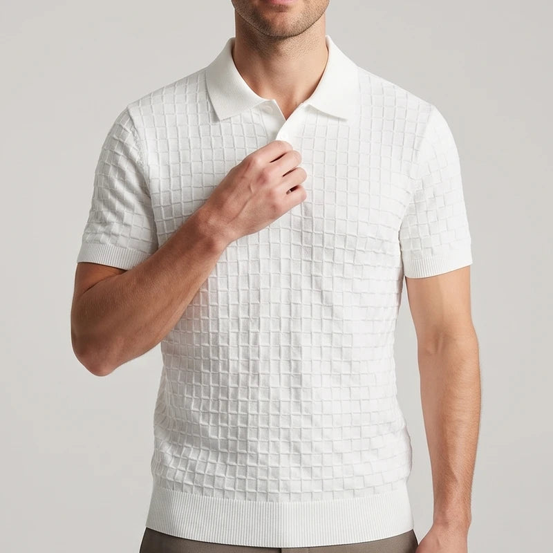 Man wearing a white short-sleeve polo shirt with a prominent waffle knit texture, adjusting the collar against a light background.