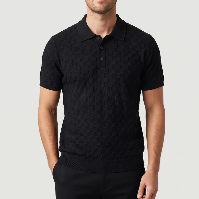 Man wearing a short-sleeve black knit polo shirt with a subtly textured checkerboard pattern and three dark buttons.