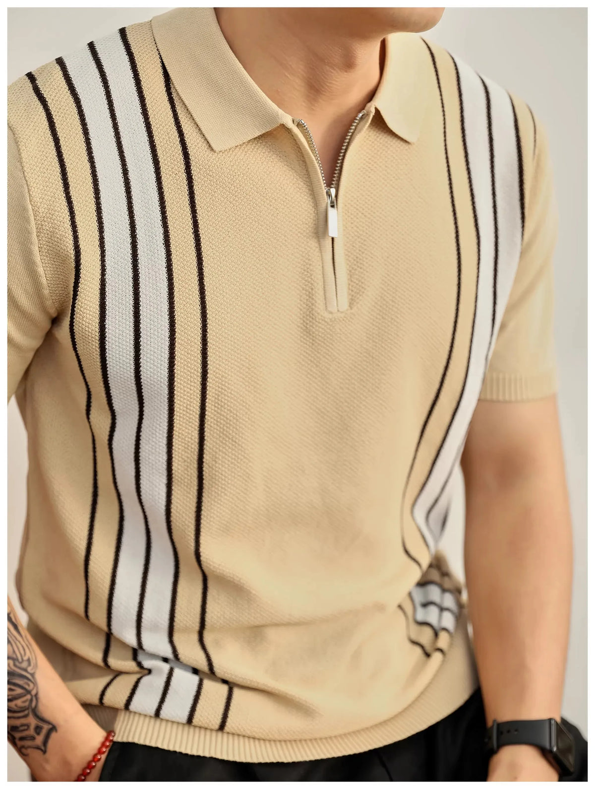 Man wearing a beige knit polo shirt with a silver zipper, black and white vertical stripes, and ribbed cuffs.