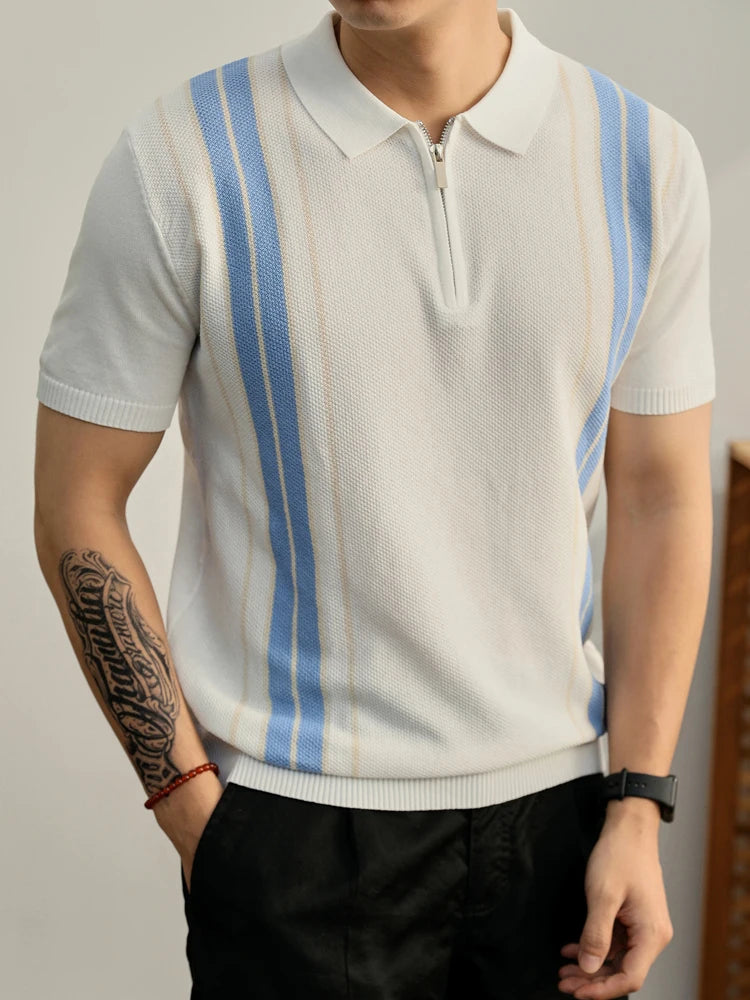 Man wearing a white knit polo shirt with blue and beige vertical stripes and a silver half-zip placket.