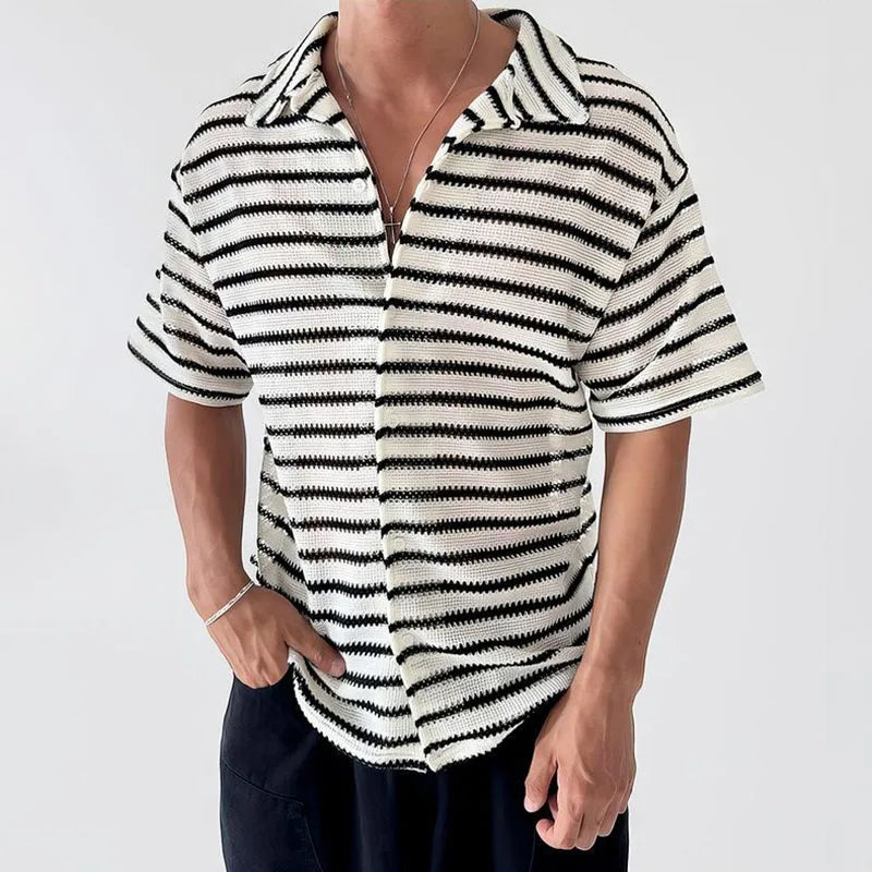 Man wearing a cream and black striped short-sleeve knit shirt with an open collar, hand in pocket.