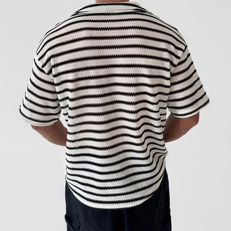 Man wearing a short-sleeved, sheer black and white striped knit shirt with a collar, viewed from the back.