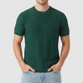 Man wearing a dark green knit short-sleeve crewneck shirt with subtle vertical ribbed texture and light blue jeans.