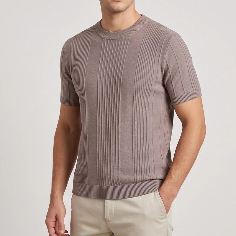 Man wearing a fitted light brown knit short-sleeve shirt with vertical ribbed detailing, paired with light beige pants.