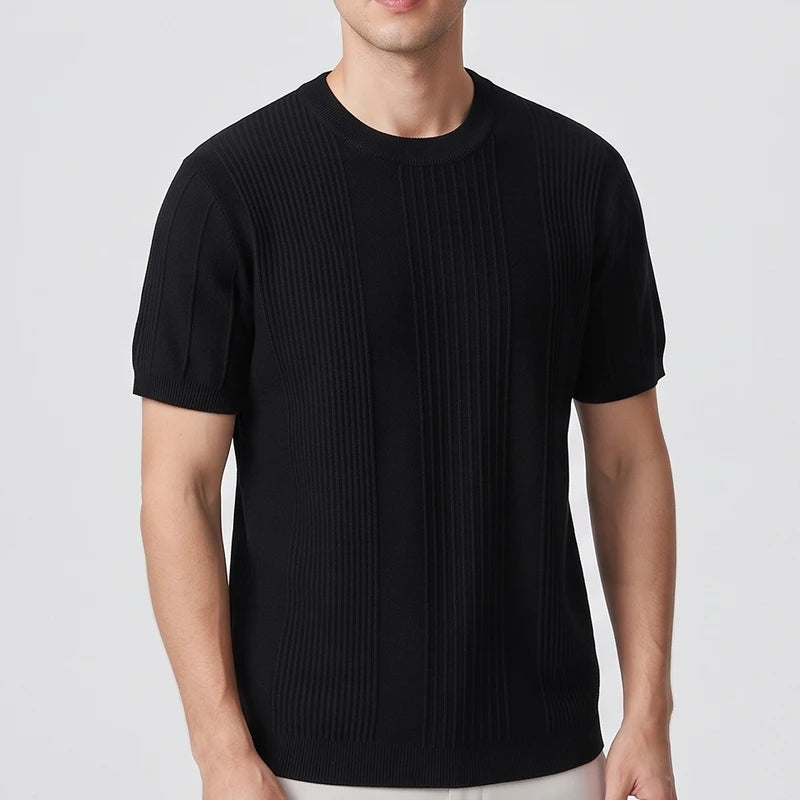Man wearing a black short-sleeve knit shirt with vertical ribbed detailing and a crewneck collar against a plain background.