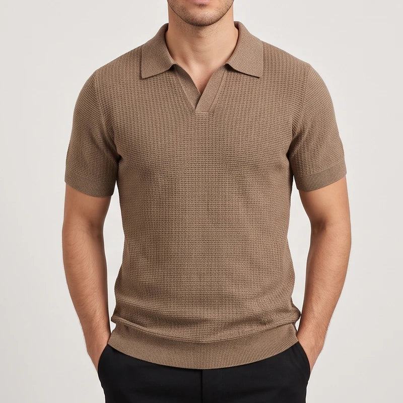 Man wearing a fitted brown knit polo shirt with a V-neck collar, short sleeves, and ribbed hem, hands in pockets.