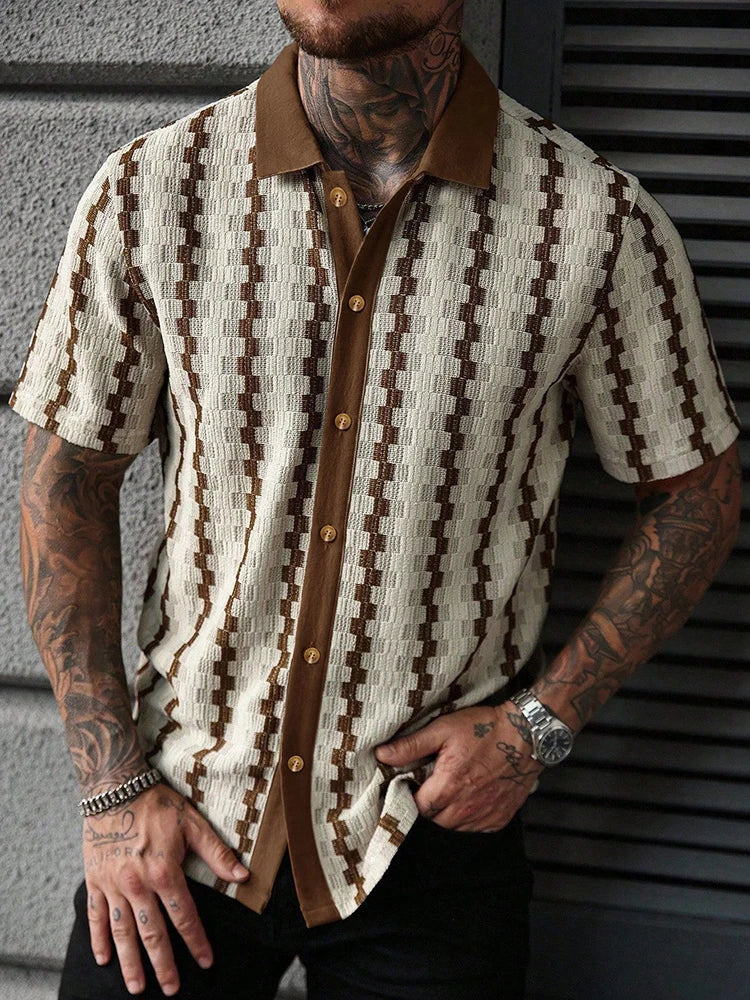 Man wearing a cream and brown short sleeve knit shirt with a patterned design and brown collar, hand in pocket.