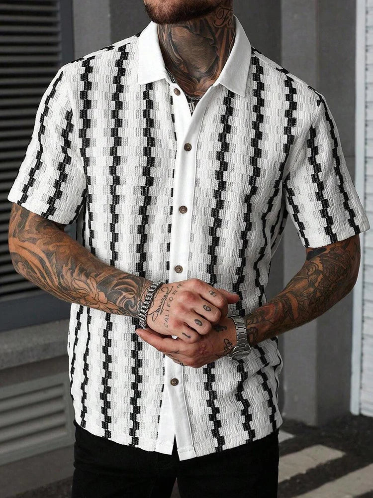 Man wearing a white knit short-sleeve shirt with vertical black textured patterns and visible chest tattoos.