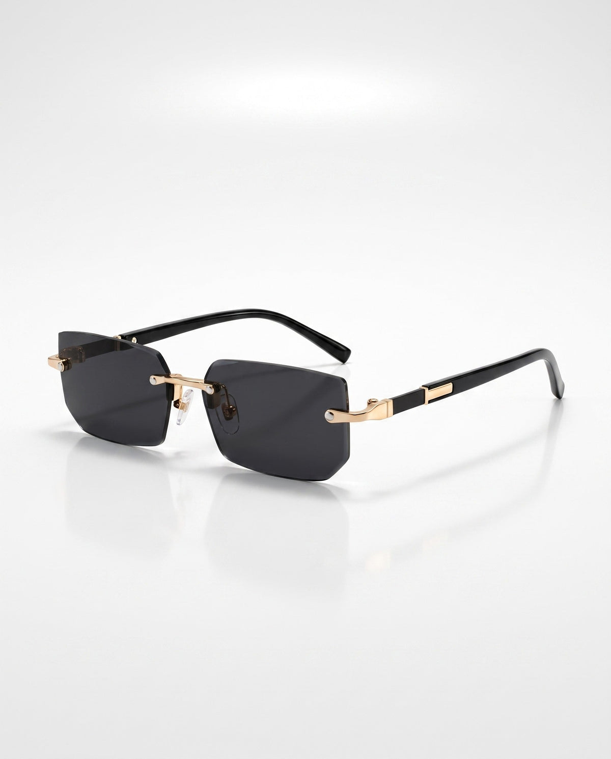 Rectangular rimless sunglasses with dark gray lenses, shiny gold bridge, and black temples on a white background.
