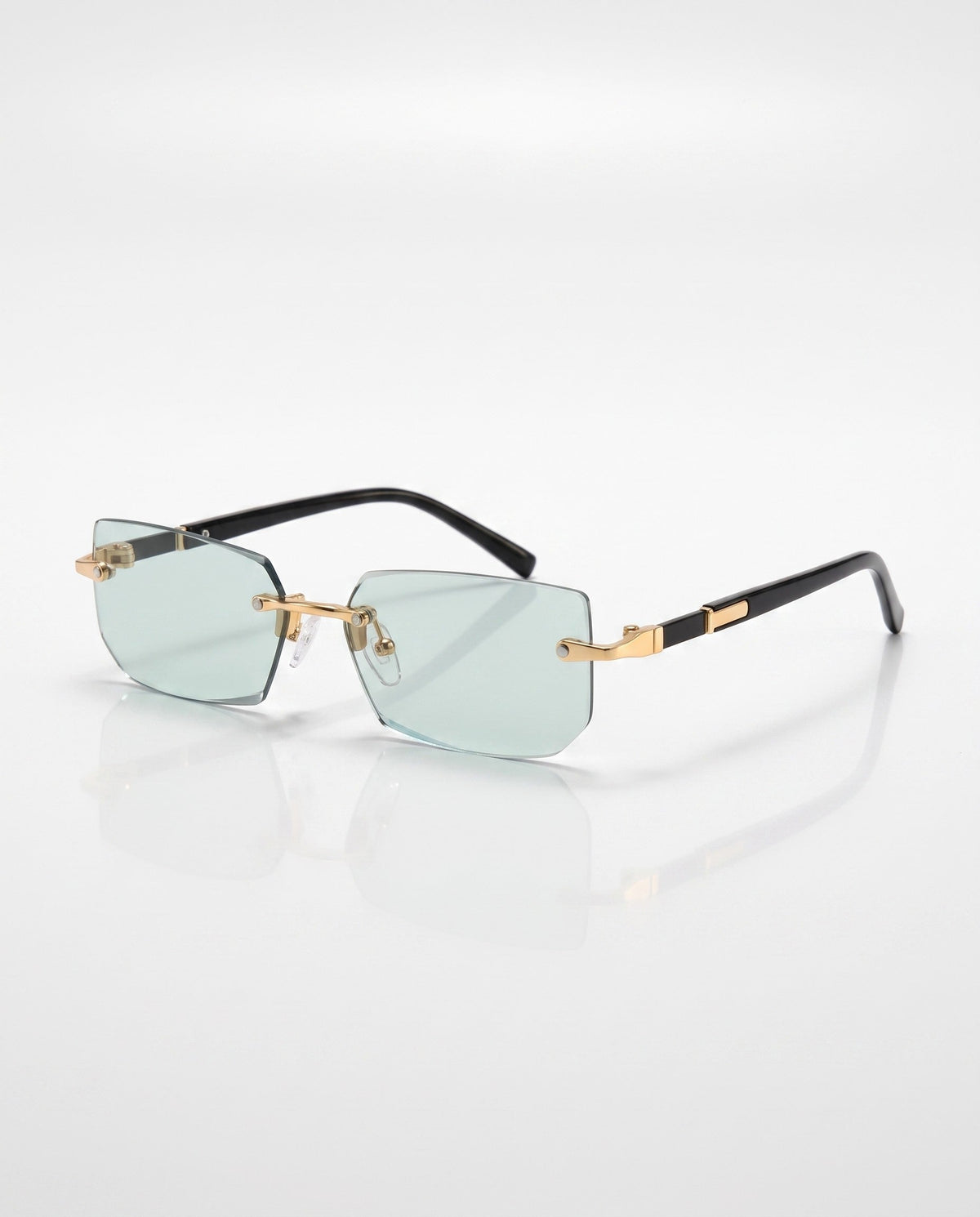 Rimless sunglasses with light blue rectangular lenses, gold hardware, and black temples, angled on a white surface.