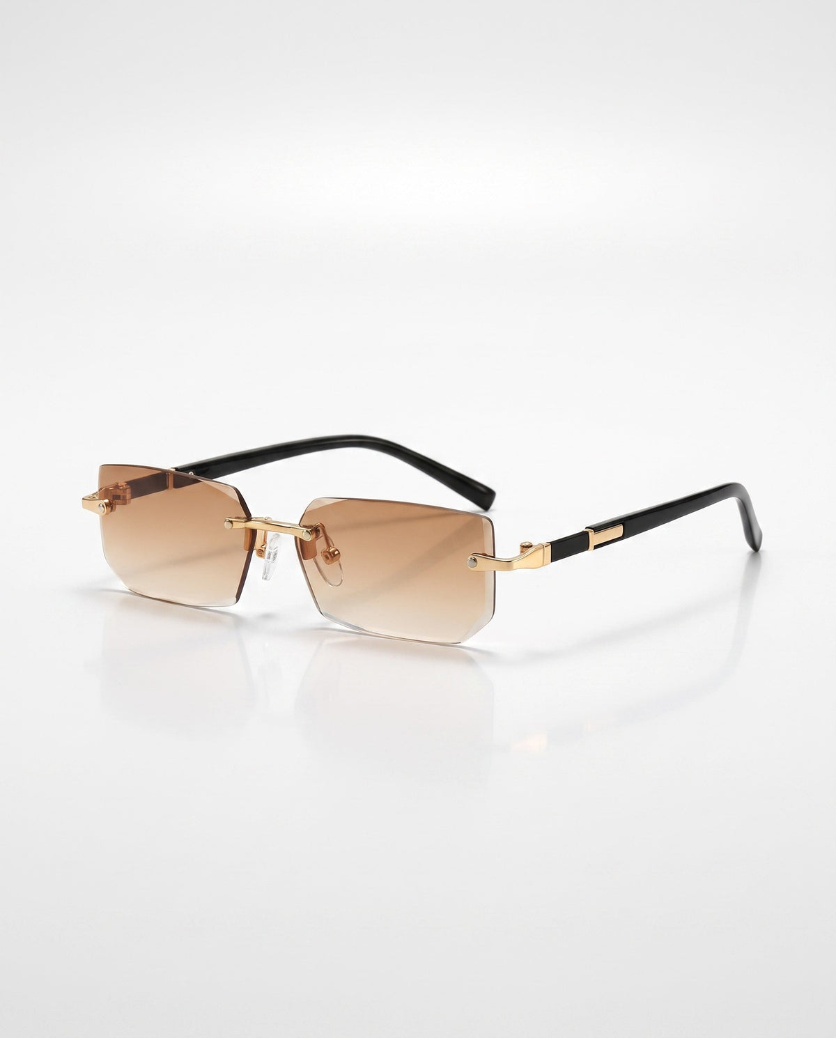 Rimless rectangular sunglasses with brown gradient lenses, gold hardware, and black arms on a white surface.