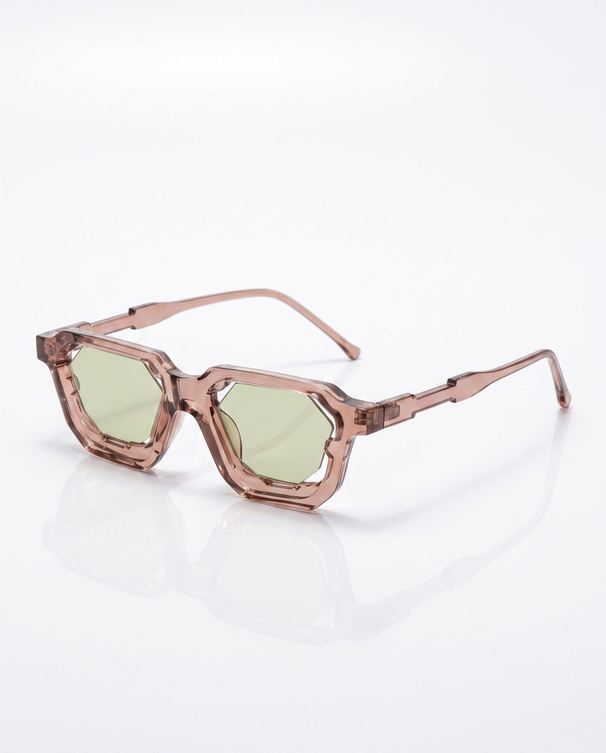 Angular translucent brown sunglasses with unique hexagonal light green lenses, resting on a white reflective surface.