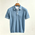 Light blue ribbed polo shirt with short sleeves, white collar, white trim, and three white buttons, hanging on a wooden hanger.