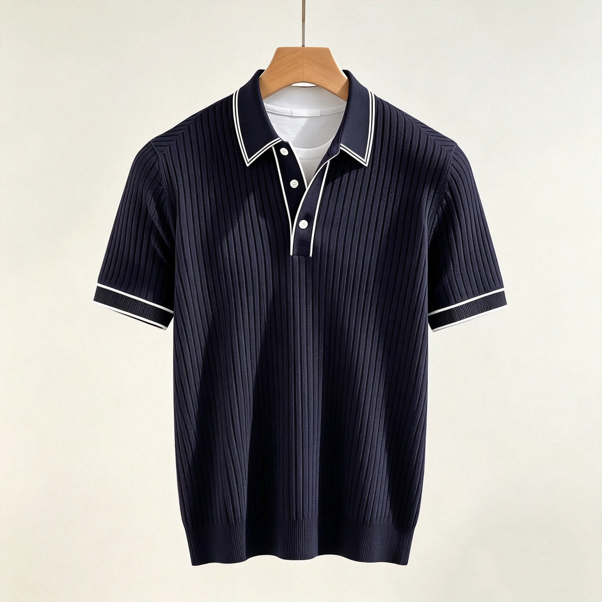 Navy blue ribbed polo shirt with white trim on the collar, placket, and short sleeves, displayed on a wooden hanger.