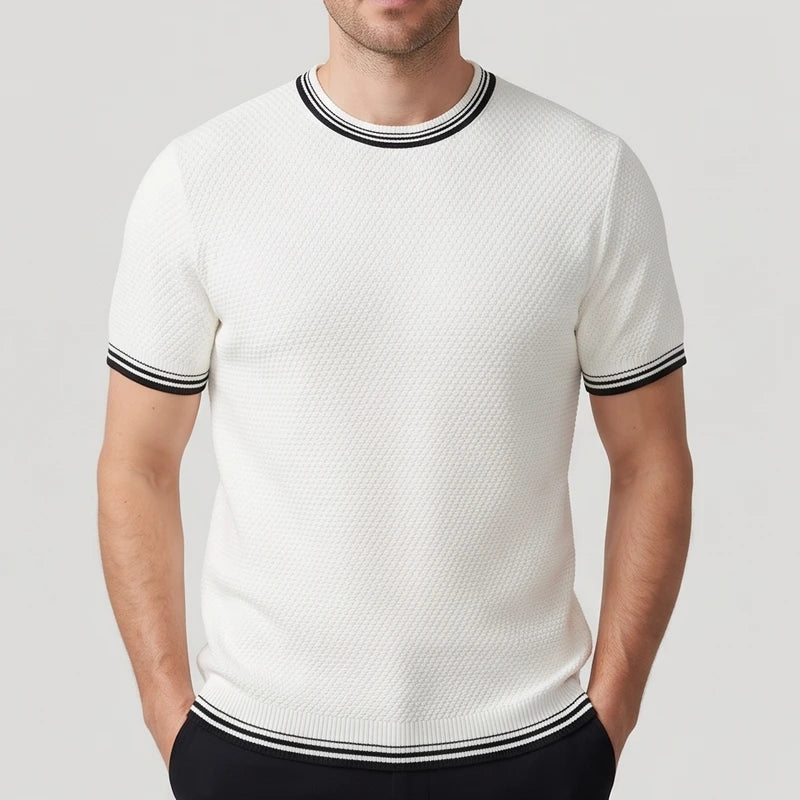 Man wearing a white textured knit short-sleeve shirt with black and white striped ribbed trim on the collar, cuffs, and hem.
