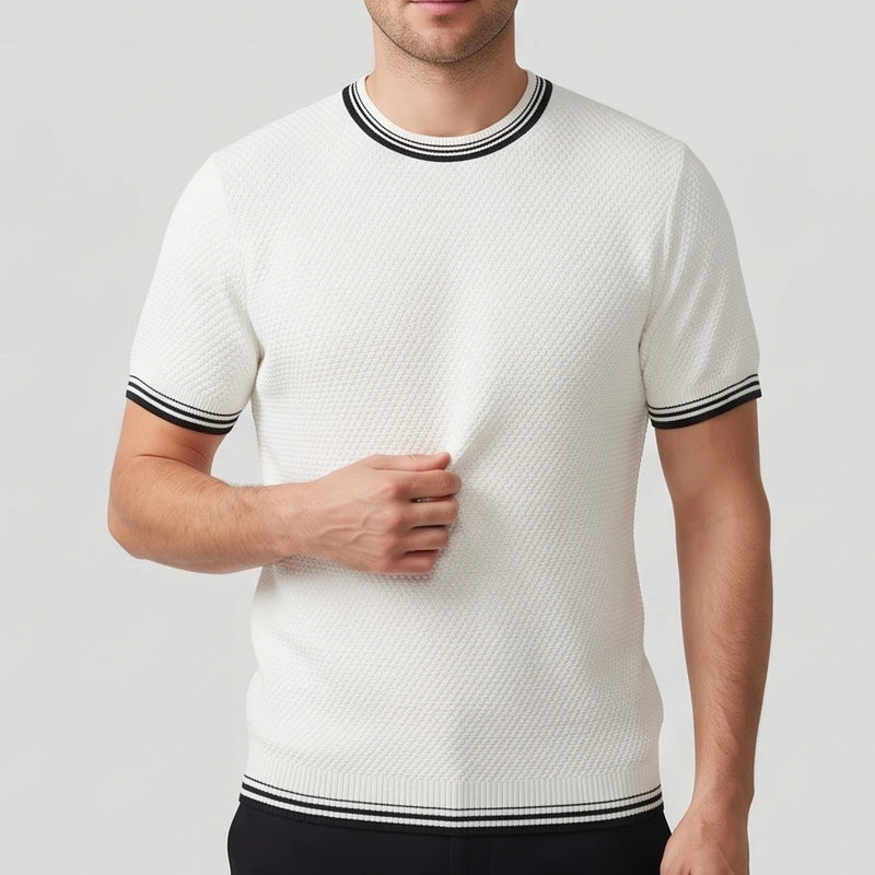 Man wearing a cream-colored textured short-sleeve shirt with black and white striped trim on the collar and sleeves.