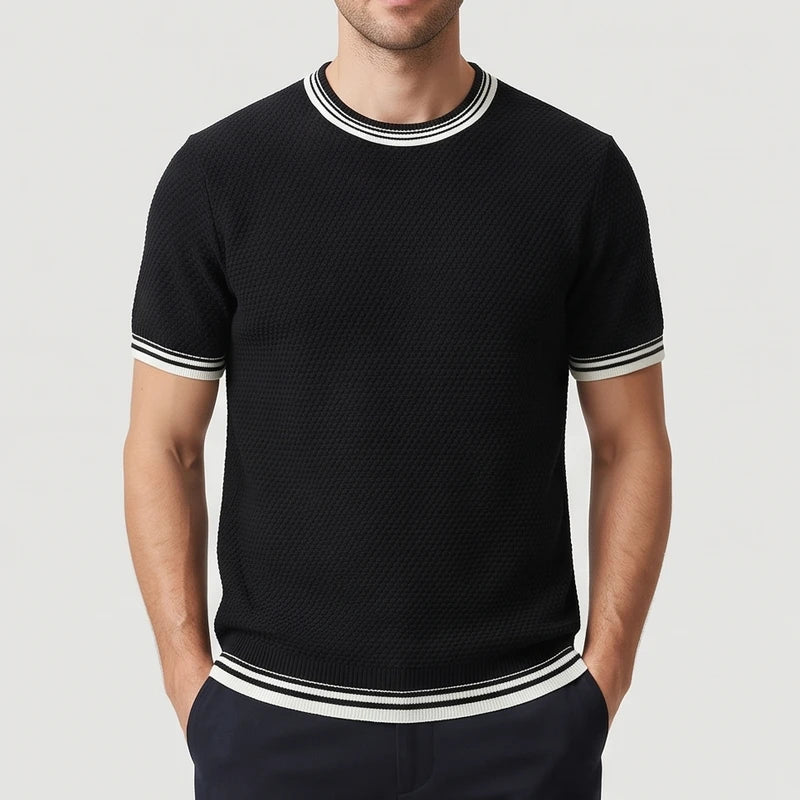 Man wearing a black short-sleeve knit shirt with white and black striped trim on the collar, cuffs, and hem.