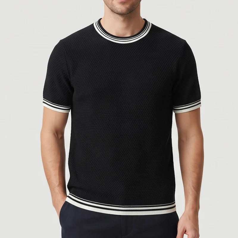 Man wearing a black textured knit short-sleeve shirt with white striped trim on the collar, cuffs, and hem.