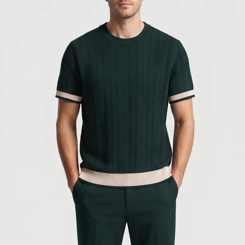 Man wearing a dark green short sleeve knit shirt with vertical cable knit texture and contrasting beige striped cuffs and hem.
