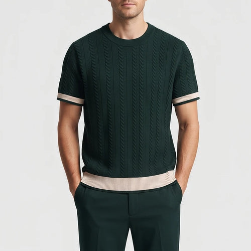 Man wearing a dark green short sleeve knit shirt with vertical cable knit texture and contrasting beige striped cuffs and hem.