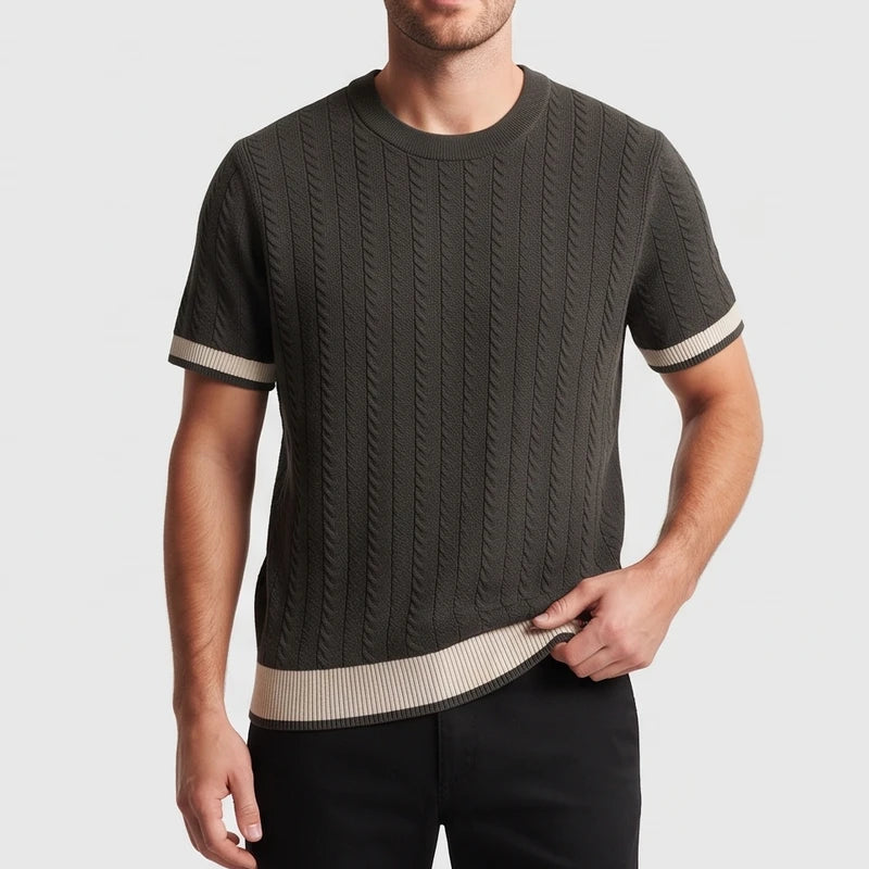 Man wearing a dark green cable knit short sleeve shirt with light beige stripes on cuffs and hem, against a plain background.