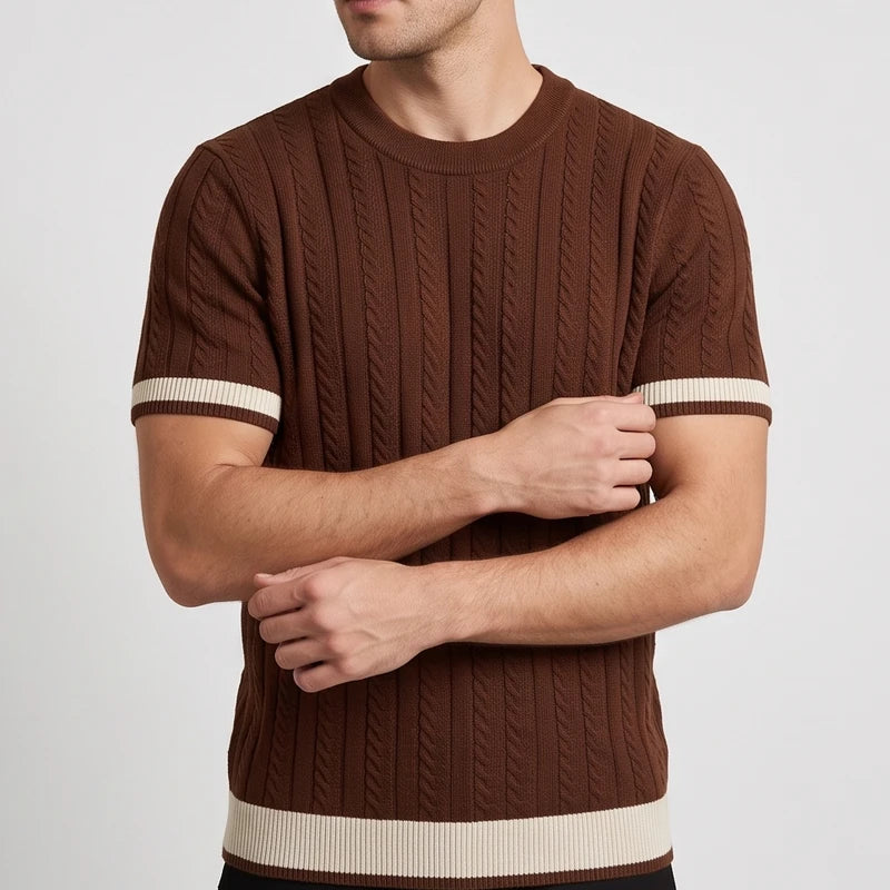 Man wearing a brown cable knit short sleeve shirt with beige stripes on the sleeves and hem, arms crossed.
