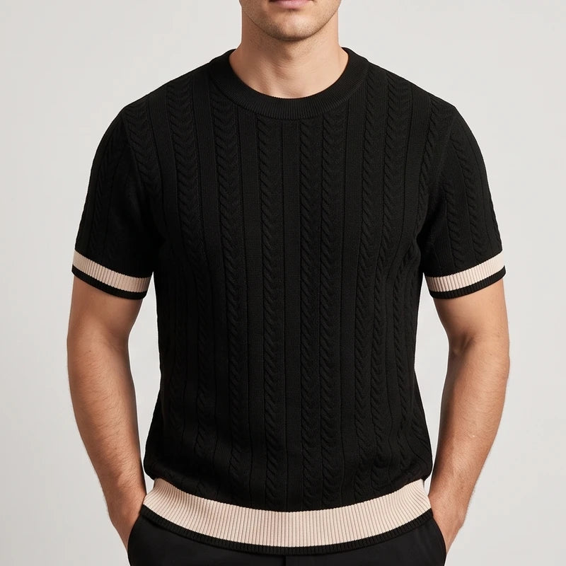 Man wearing a black short sleeve knit shirt with cable knit texture, light tan stripes on the sleeves, and a matching hem.