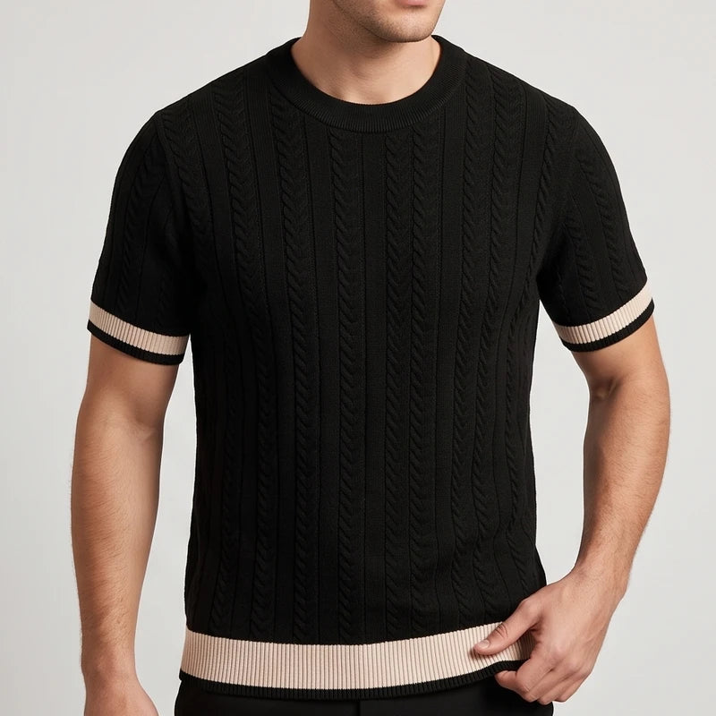 Man wearing a black cable knit short-sleeve shirt with light beige striped cuffs and hem against a white background.